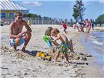 A dad watching his son playing in the sand at SUN OUTDOORS REHOBOTH BAY - thumbnail