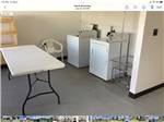 Washer and dryer with white table for folding at SLEEPING WOLF CAMPGROUND & RV PARK - thumbnail