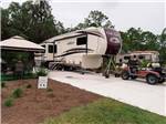 A golf cart parked next to a fifth wheel at KEYSTONE HEIGHTS RV RESORT - thumbnail