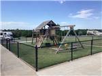 The fenced in playground equipment at WANDERLUST CROSSINGS RV PARK - thumbnail