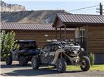 Two ATVs parked in front of a cabin at CASTLE GATE RV PARK & CAMPGROUND - thumbnail