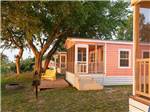 A colorful rental cabin with chairs in the front at OUTER BANKS WEST/CURRITUCK SOUND KOA HOLIDAY - thumbnail