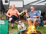 A couple drinking wine sitting with their dog at OUTER BANKS WEST/CURRITUCK SOUND KOA HOLIDAY - thumbnail