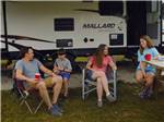 A family sitting outside of a motorhome at BIGFOOT ADVENTURE RV PARK & CAMPGROUND - thumbnail