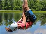 A young child ziplining over the pond at BIGFOOT ADVENTURE RV PARK & CAMPGROUND - thumbnail