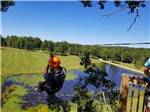 A man zip lining over the pond at BIGFOOT ADVENTURE RV PARK & CAMPGROUND - thumbnail