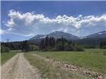 Gravel road leads toward forest and mountains at RED EAGLE CAMPGROUND - thumbnail