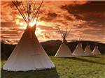 A row of teepees with a beautiful sunset in the background at CHEWING BLACK BONES CAMPGROUND - thumbnail
