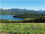 A grassy field with a lake and mountain at COPPER COURT RV PARK - thumbnail