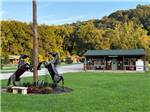 Statues of rearing horses near flagpole in front of campground building at PINE CREEK CABINS AND CAMPGROUND - thumbnail