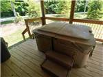 Hot tub that is covered on wooden deck at PINE CREEK CABINS AND CAMPGROUND - thumbnail