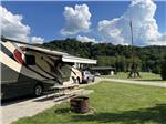 Motorhome with awning extended near picnic table and fire pit at PINE CREEK CABINS AND CAMPGROUND - thumbnail