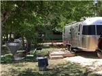 Shaded campsite with deck and Airstream at OFF THE VINE RV PARK - thumbnail