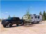 A black truck and trailer parked in a dirt site at LITTLE AMERICA RV PARK - thumbnail