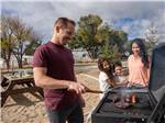 The dad barbecuing while the family looks on at LITTLE AMERICA RV PARK - thumbnail