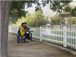A couple sitting on a bench under a tree at PECHANGA RV RESORT - thumbnail