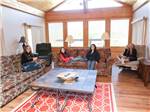 Girls on sofas and recliner watching television at DENTON FERRY RV PARK & CABIN RENTAL - thumbnail