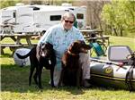 Man kneeling with two dogs near a raft at DENTON FERRY RV PARK & CABIN RENTAL - thumbnail