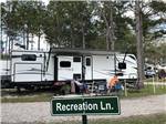 Parked trailer with couple and sign reading Recreation Ln at LAKE CITY RV RESORT - thumbnail