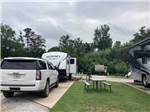 A trailer and SUV parked in a site at EAGLE'S LANDING RV PARK - thumbnail