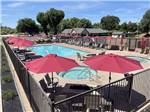 Tables and chairs with red umbrellas around the pool at KINGS RIVER RV RESORT - thumbnail
