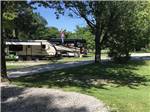 Trailer and big rig parked in site with trees at SINGING HILLS RV PARK - thumbnail