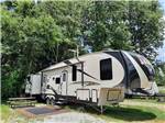A fifth wheel trailer in a back in RV site at SINGING HILLS RV PARK - thumbnail