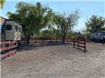 A gravel RV site with a fence at BOOT HILL RV RESORT - thumbnail