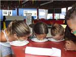 Children having a pie eating contest at STATELINE CAMPRESORT & CABINS - thumbnail