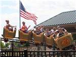 Rollercoaster careening around a curve with flag in background at WYLIE PARK CAMPGROUND & STORYBOOK LAND - thumbnail