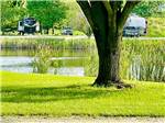 Tree and lake with campers in campsites at NEW VISION RV PARK - thumbnail