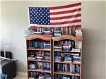 A book shelf with a USA flag hanging above it at RV HIDEAWAY CAMPGROUND - thumbnail