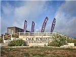 The front entrance sign with Welcome flying flags at OAK FOREST RV RESORT - thumbnail