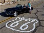 A man and lady parked in the road next to the Route 66 symbol at PIRATE COVE RESORT & MARINA - thumbnail