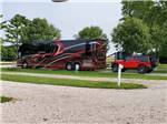 A motorhome pulling a Jeep in a pull thru gravel RV site at KAMP KOMFORT RV PARK & CAMPGROUND - thumbnail