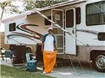 A man with a trash bag standing under an RV awning at LAKESIDE RV RESORT BY RJOURNEY - thumbnail