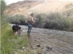 A man fishing with his dogs behind him at WHISKEY FLATS RV PARK - thumbnail