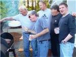 A bunch of men looking at a BBQ pit at TOUTLE RIVER RV RESORT - thumbnail