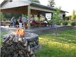 The fire pit with a fire in front of an outdoor covered sitting area at TOUTLE RIVER RV RESORT - thumbnail