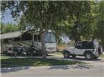 A class A motorhome and Jeep in a back in site at BAKERSFIELD RIVER RUN RV PARK - thumbnail