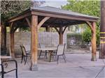 Wooden gazebo with a table and chairs at BAKERSFIELD RIVER RUN RV PARK - thumbnail
