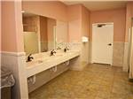 Pink hued restrooms with multiple sinks at EZ DAZE RV PARK - thumbnail
