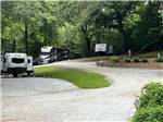 A road going up to RV sites at A motorhome in a gravel RV site with a patio at FRANKLIN RV PARK & CAMPGROUND - thumbnail