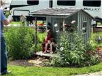 A little girl having her picture taken by a small house at A motorhome in a gravel RV site with a patio at FRANKLIN RV PARK & CAMPGROUND - thumbnail