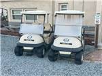 Two golf carts parked next to a building at FOUR OAKS LODGING & RV RESORT - thumbnail