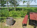 Picnic table and fire pit near water at CAMPING POKEMOUCHE - thumbnail