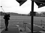 Black and white photo of golfer swinging at the driving range at RIVERSIDE GOLF & RV PARK - thumbnail