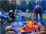 A group of people watching a man move the fire in the fire pit at LONE MOUNTAIN RESORT - thumbnail