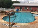 Swimming pool and hot tub adjacent to the enclosed rec hall and game room at COFFEE CREEK RV RESORT & CABINS - thumbnail