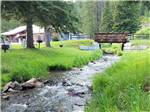 Stream rushes under a bridge and past grassy banks at FISH'N FRY CAMPGROUND & RV PARK - thumbnail